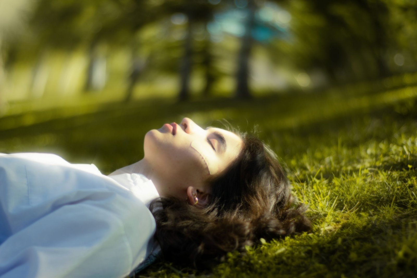 Healing Emotional Trauma: A Complete Guide to Emotional Growth and Healing A serene portrait of a woman lying down on grass, eyes closed and relaxed in nature.